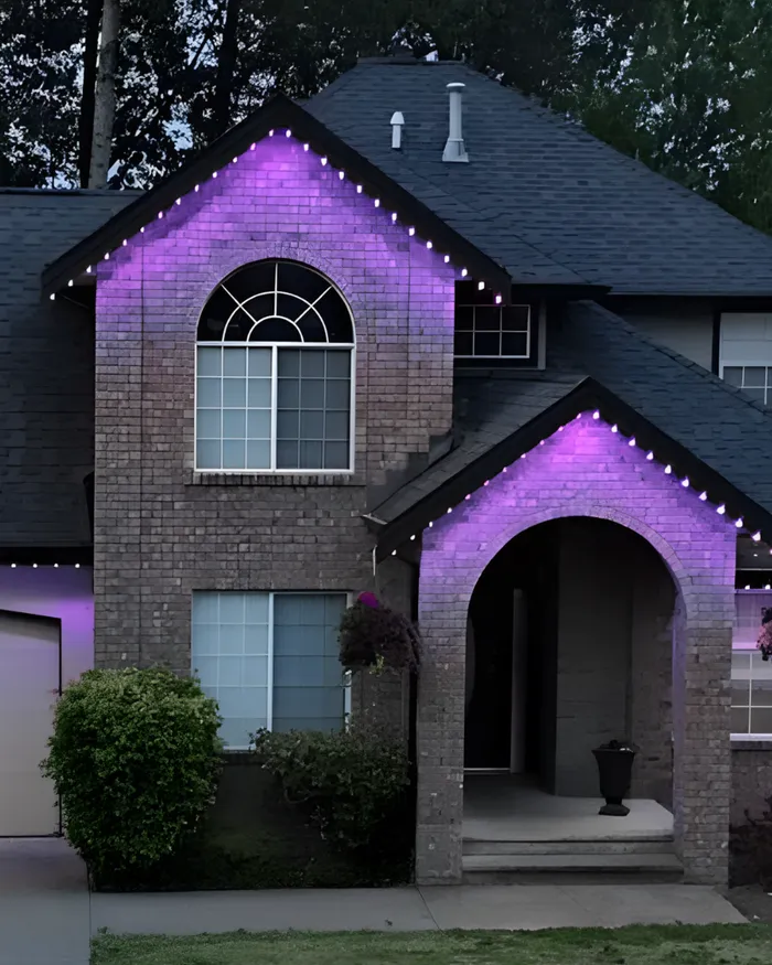A brick two-storey house with its gables washed in purple light.